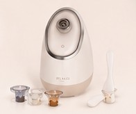 AURA steamer with three aromatherapy pods and a cleaning brush